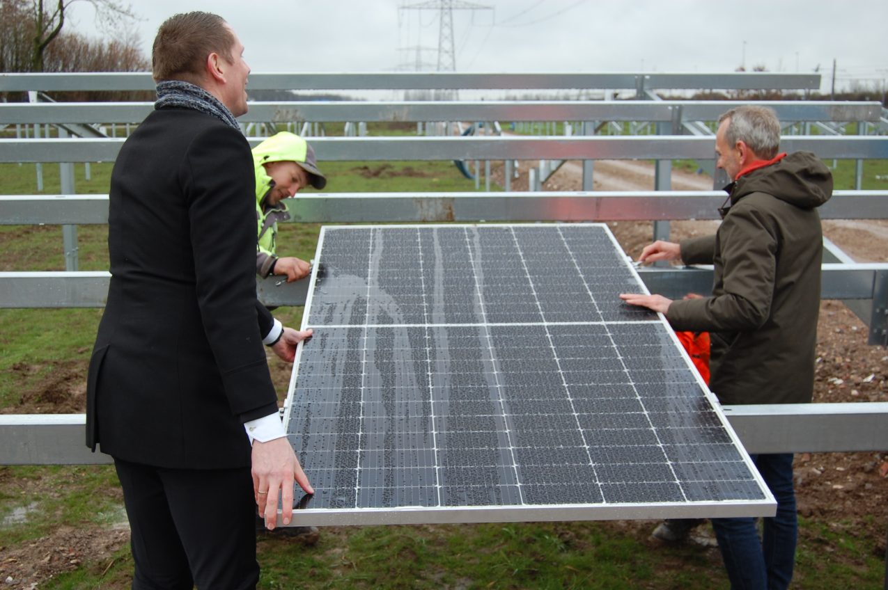 Wethouder Dimitri Horsthuis legt eerste paneel zonnepark Overbetuwe.